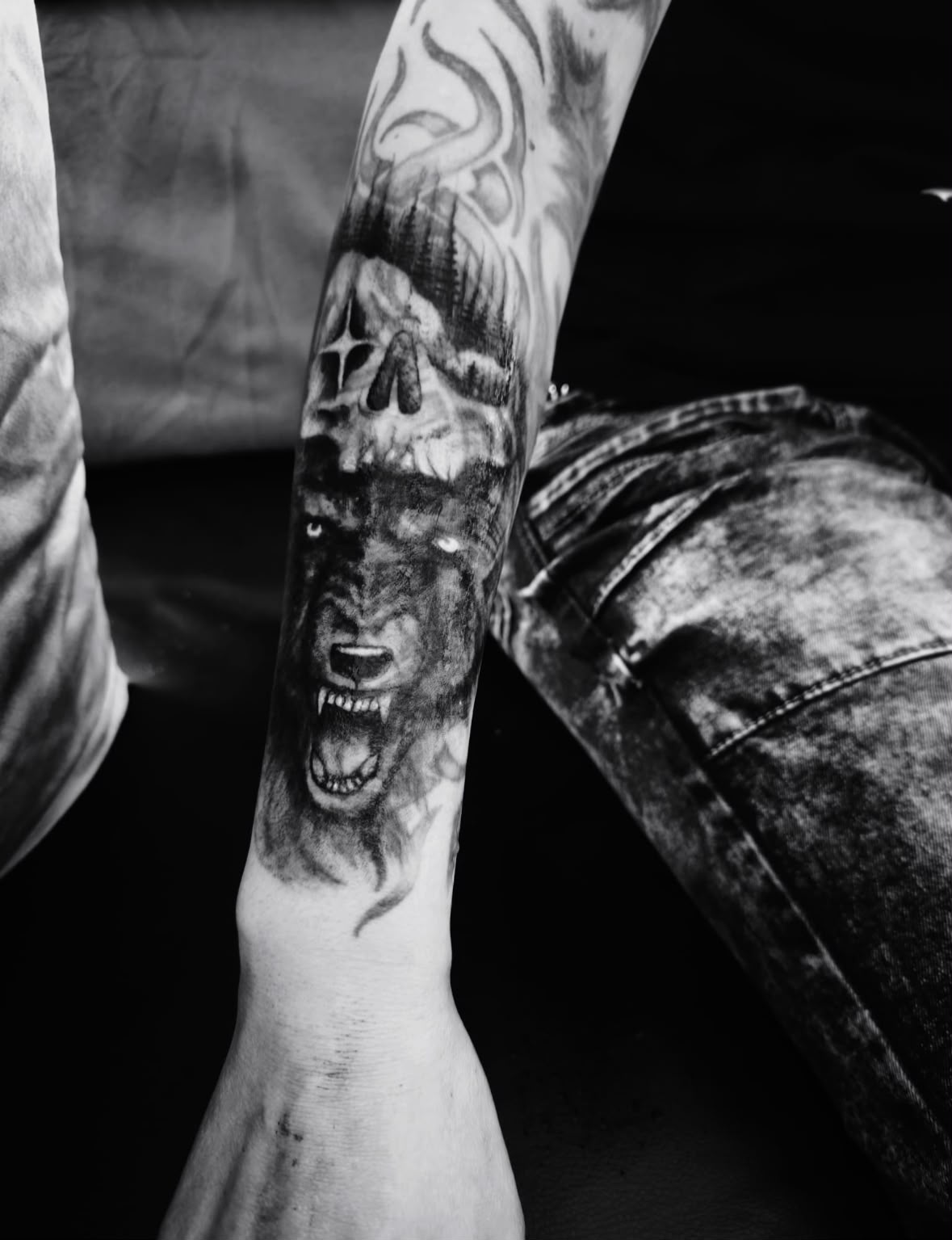 Realistisches Wolf-Tattoo mit Totenkopf und Waldmotiv am Unterarm