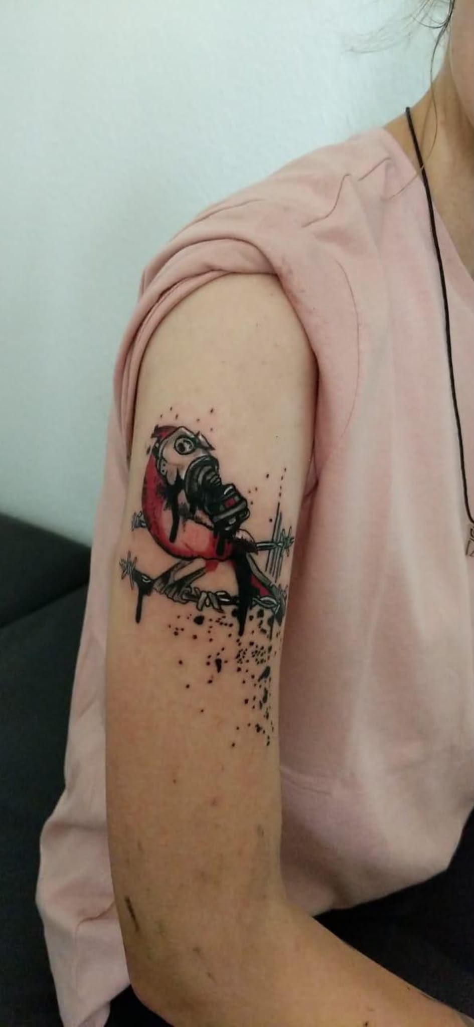 Farbiges Gasmasken-Tattoo mit Stacheldraht am Oberarm