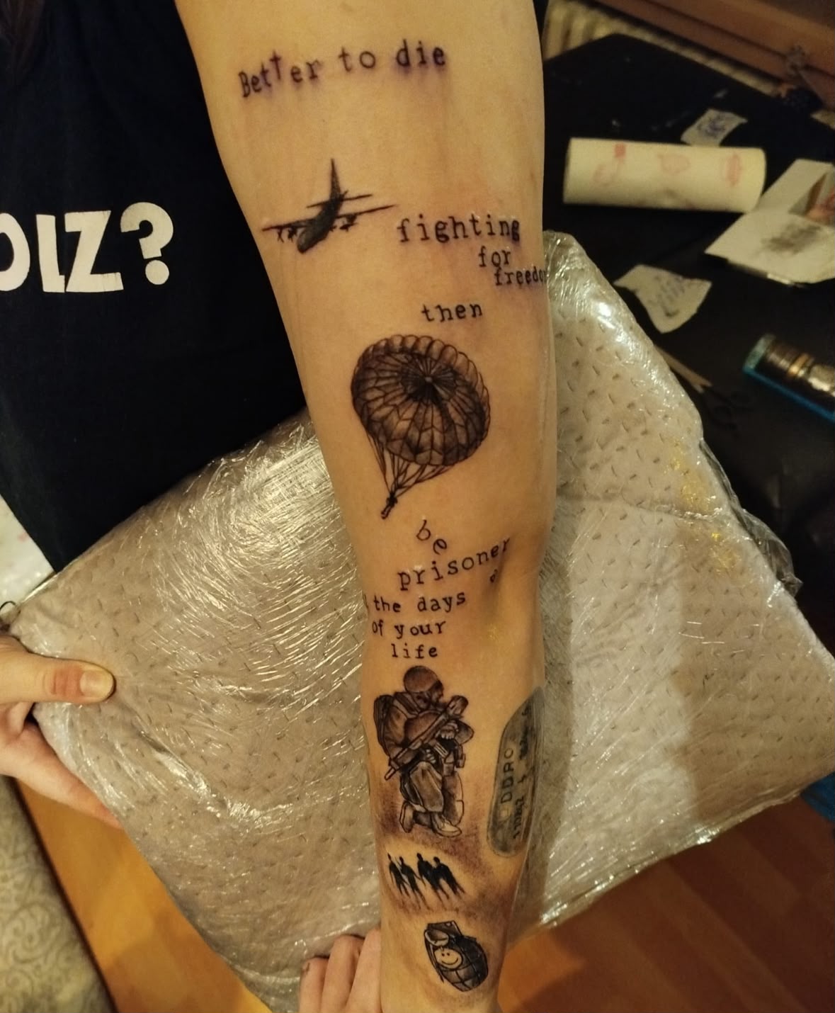 Schriftzug-Tattoo mit Fallschirm und Soldat am Unterarm